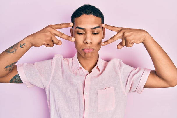 Young african american guy doing victory sign and peace gesture depressed and worry for distress, crying angry and afraid. sad expression.  - Fotó, kép