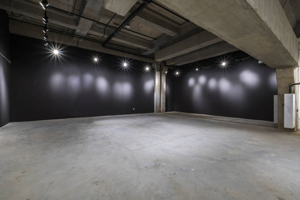 empty interior of large concrete room as warehouse or hangar with spotlights - Foto, afbeelding