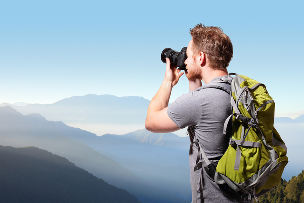 Young man taking photo on top of mountain - Valokuva, kuva