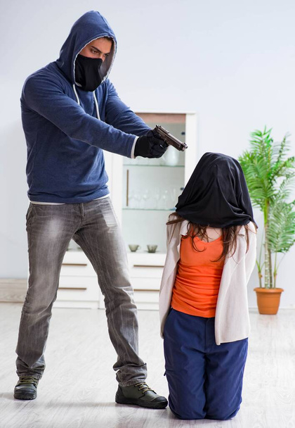 Hombre armado agrediendo a una joven en casa - Foto, imagen