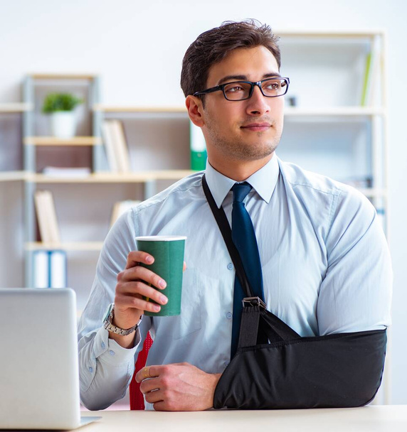 Businessman with broken arm working in office - Foto, imagen