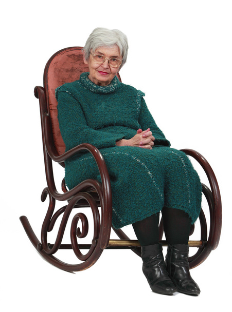 Old woman sitting on a wooden rocking chair isolated against a white background. - Foto, Imagem