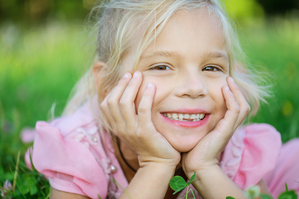 schönes lächelndes Mädchen liegt auf grünem Gras - Foto, Bild