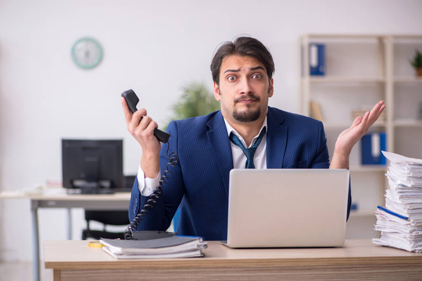 Junge männliche Angestellte unzufrieden mit exzessiver Arbeit im Büro - Foto, Bild