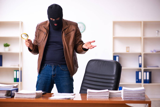 Egy maszkos fiatalember információt lop az irodából. - Fotó, kép