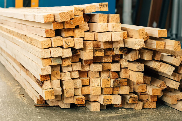 In einer Tischlerei oder einem Sägewerk liegen Holzbalken auf dem Boden. Hintergrund für einen Hersteller von Baustoffen aus Holz. - Foto, Bild