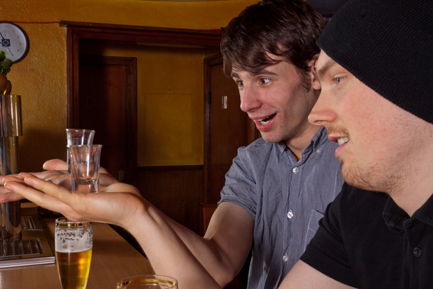 Two friends sitting in a pub and drinking hard liquor - Foto, immagini