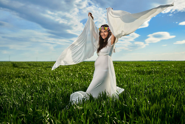 Junge schwangere Frau in einem dampfenden weißen Kleid in einem Weizenfeld - Foto, Bild
