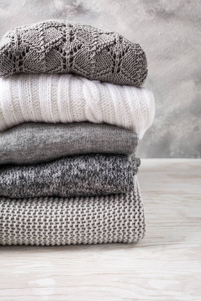 Pile de pulls tricotés confortables et pulls sur fond en bois. Concept automne et hiver - Photo, image