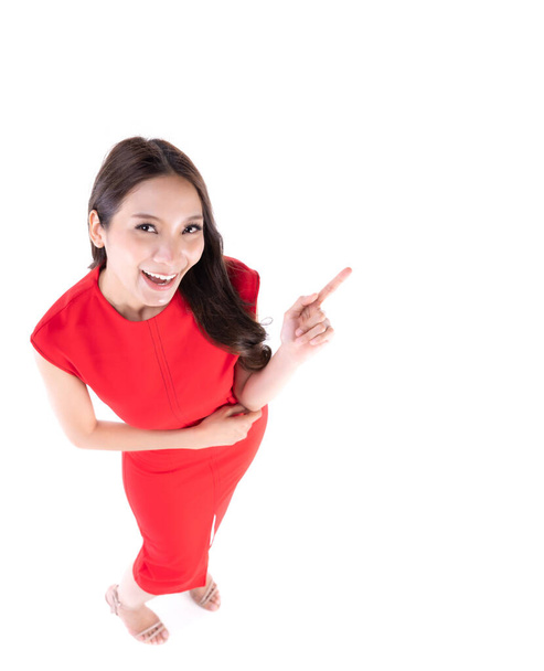 Imagen de sentirse sonriente y feliz. Mujer asiática joven sonriendo con los dientes apuntando hacia arriba con el dedo índice para copiar el espacio. Concepto de expresiones y emociones faciales femeninas. - Foto, imagen