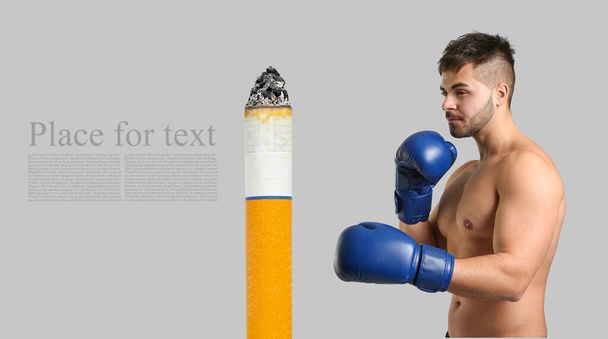 Sporty male boxer and cigarette on grey background with space for text - Photo, Image