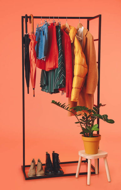 Rack with stylish clothes, shoes and umbrellas on color background - Fotoğraf, Görsel