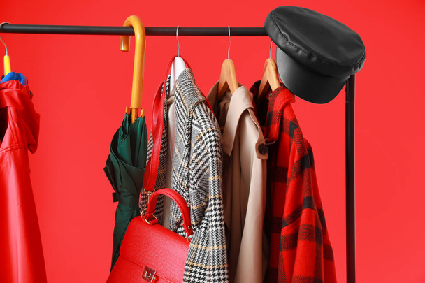 Rack met stijlvolle kleding en accessoires op kleur achtergrond - Foto, afbeelding
