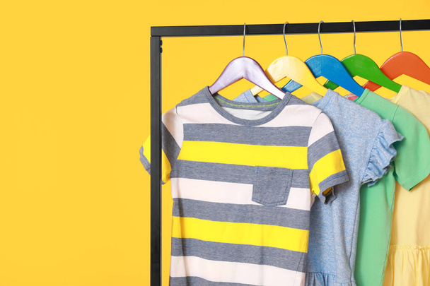 Rack met stijlvolle kleding op kleur achtergrond, closeup - Foto, afbeelding