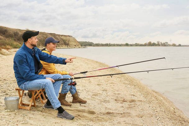 Батько і син рибалять разом на річці
 - Фото, зображення