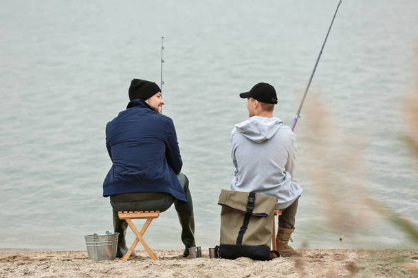 Отец и сын рыбачат вместе на реке - Фото, изображение