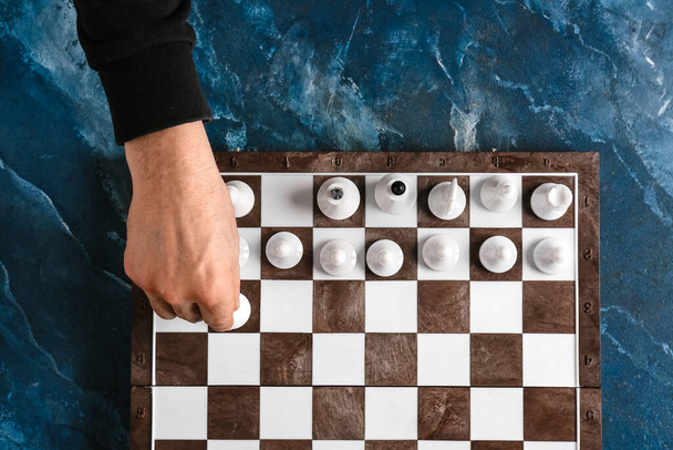 Man playing chess on color  background - Foto, afbeelding