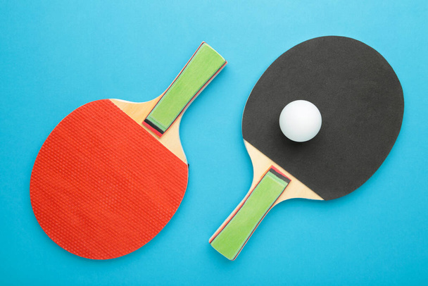 Ping pong rackets and ball on blue background. Top view - Fotó, kép