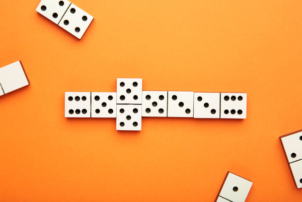 Playing dominoes on a orange table. Domino effect. Top view - Foto, imagen