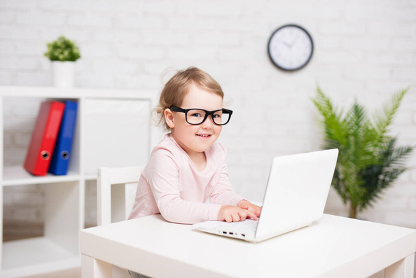 concept d'enfance, d'éducation, d'affaires et de technologie portrait d'une jolie petite fille dans de grandes lunettes à l'aide d'un ordinateur portable à la maison ou en classe - Photo, image
