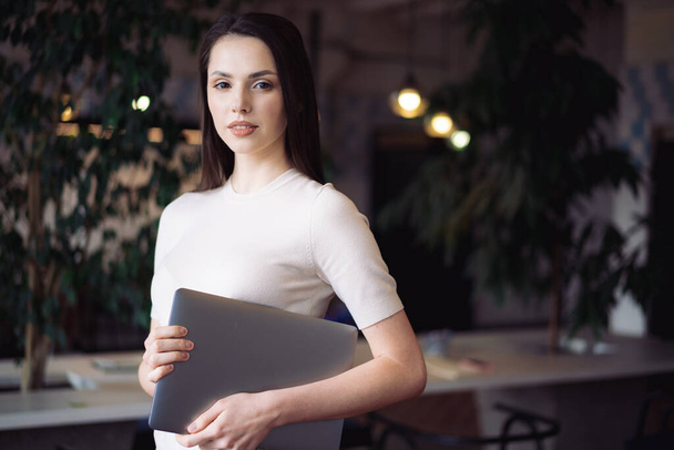 Portrait of young casual woman holding laptop - Fotó, kép