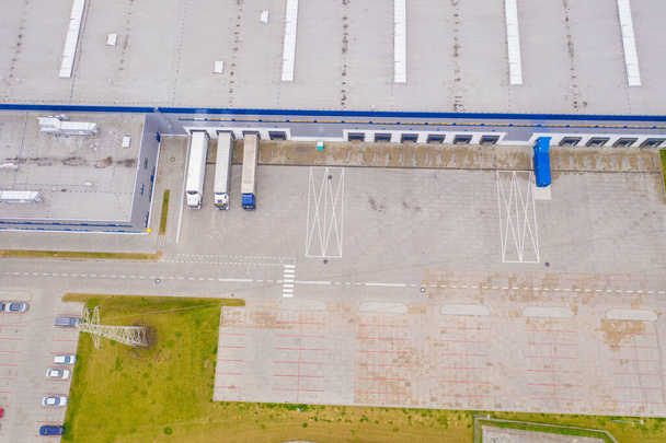 Vista aérea del almacén de mercancías. Centro logístico en zona industrial de ciudad desde arriba. Vista aérea de camiones cargando en el centro logístico. Vista desde el dron. - Foto, Imagen