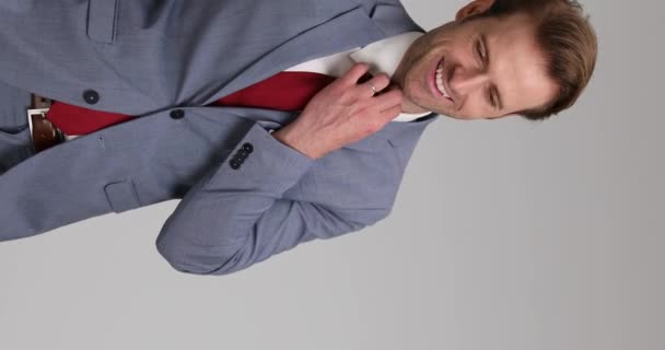 vidéo verticale d'un bel homme d'affaires fixant sa cravate, riant, mettant ses mains dans ses poches et laissant - Séquence, vidéo