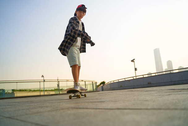 adolescent asiatique enfant skateboard à l'extérieur sur un piéton pont - Photo, image