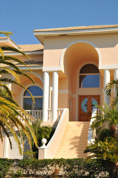 Entrada de dos pisos que conduce a las puertas dobles de esta elegante mansión en la bahía. Las palmeras denotan su ubicación tropical
. - Foto, imagen