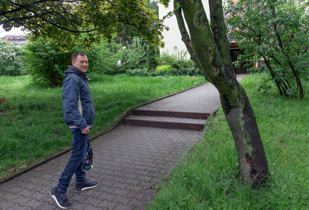 μεσήλικας, 60 ετών, περπατά στο μονοπάτι της πλατείας και χαμογελά - Φωτογραφία, εικόνα