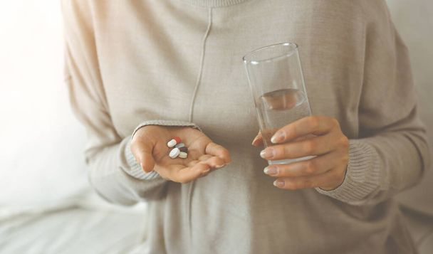 Close-up woman holding pills time to take medications, cure for headache. Medicine concept during self isolation and Coronavirus pandemic - Foto, Imagen