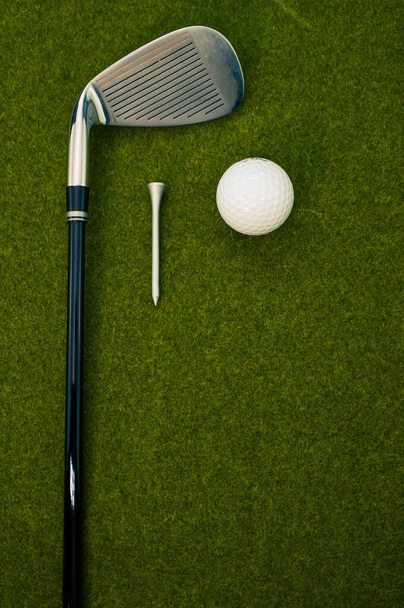 A vertical shot of a golf club, ball, and a tee on the grass with a copy space - Foto, immagini