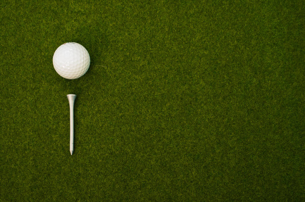 A top view of a golf ball and a tee on the grass with a copy space - Φωτογραφία, εικόνα