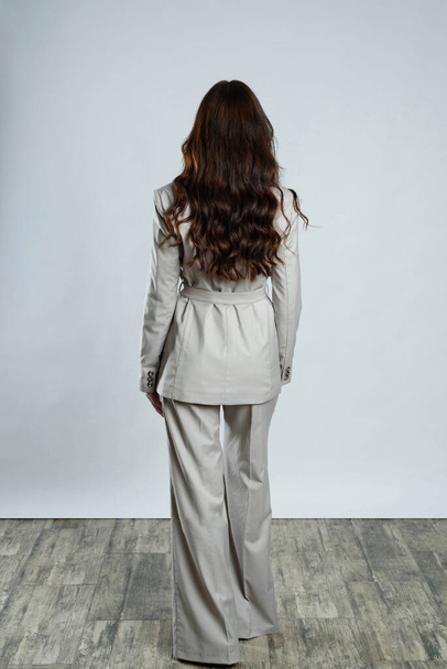長い巻き毛の灰色のスーツの女性の背中 - 写真・画像