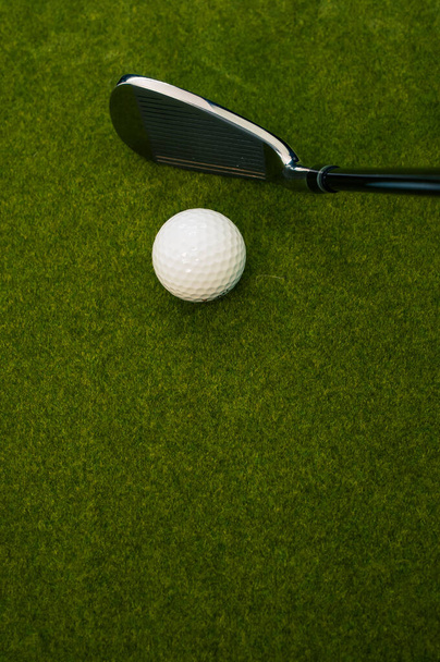 A vertical shot of a golf club and a ball on the grass with a copy space - Photo, Image