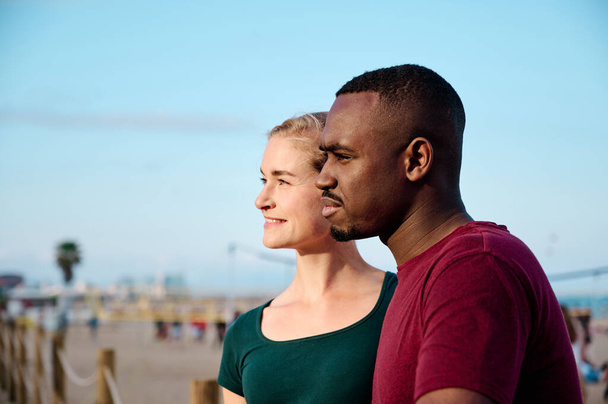 giovane coppia multietnica in spiaggia guardando fuori dalla fotocamera con spazio copia - Foto, immagini