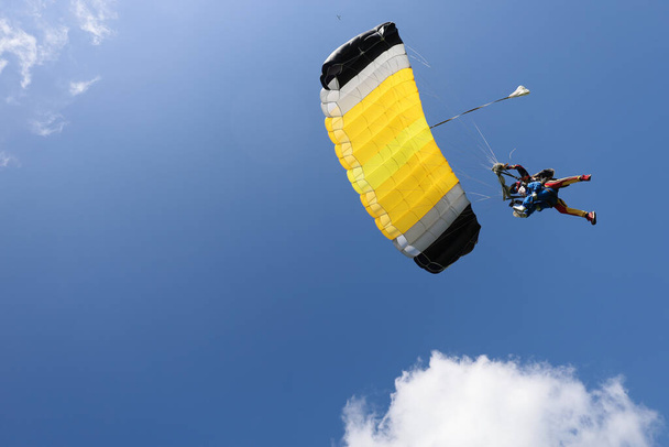 Hava dalışı. Çift atlama. Güzel bir kız, eğitmeni ve büyük sarı bir paraşüt.. - Fotoğraf, Görsel