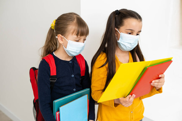 Close-up portret van twee leuke aantrekkelijke meisjes met een veiligheidsmasker. stoppen met influenza ziekte pandemie - Foto, afbeelding