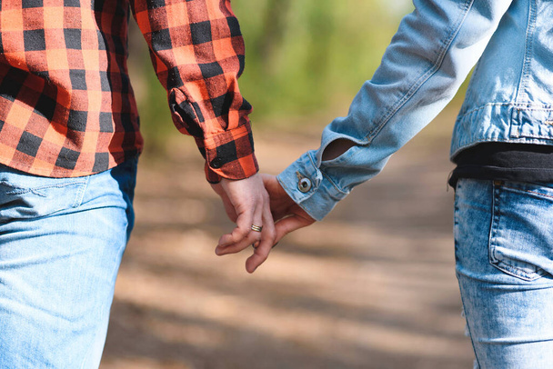 paar in jeans hand in hand in zonnig park - Foto, afbeelding