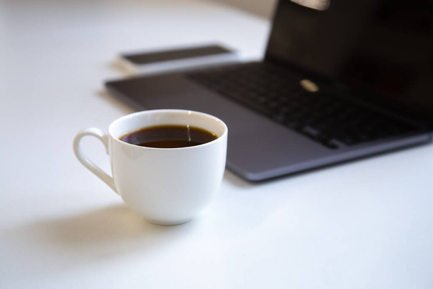 A cup of black coffee at the workplace in the office close-up. - Zdjęcie, obraz