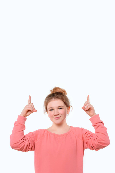 Your promo here. Portrait of attractive young girl pointing fingers up, showing good shopping site, recommend click link, upload app or subscribe. Studio shot, white background - Photo, Image