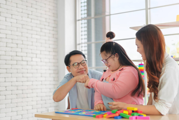 Happy asian father and mother playing education toy with their daughter down syndrome child in living room, Dad giving fist bump with daughter, Activity happy family lifestyle concept. - Foto, Imagen