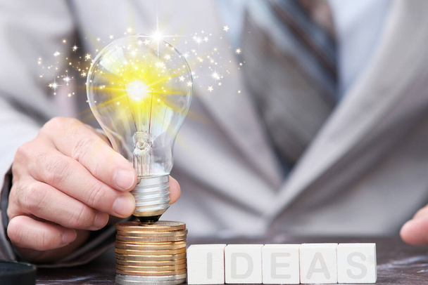 Businessman hand light bulb on cions ,idea innovation and inspiration concept, New ideas in the future - Photo, Image
