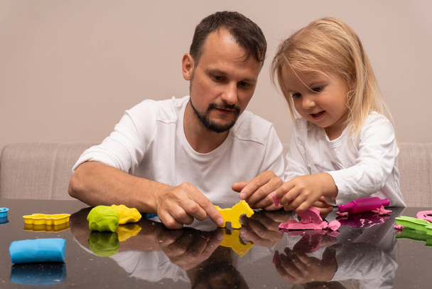 Father plays with child with colorful animals made from playdough - Photo, image