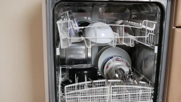 Limpie los platos en un lavavajillas abierto después del lavado. Muchos utensilios, tenedores, cucharas, platos, sartenes, limpios y brillantes - Metraje, vídeo