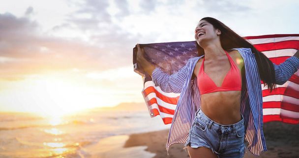 Happy woman smiling and running on beach while celebrateing independence day and enjoying freedom in USA - Foto, Imagen