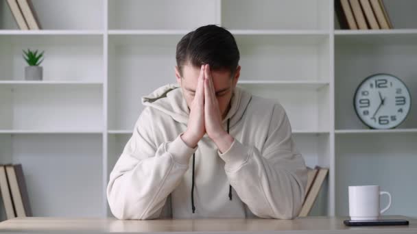 Namaste jestinde el ele tutuşan dalgın bir adam masasında gözleri kapalı oturuyor. Modern ofiste dua eden erkek kameraya bakar ve ellerini yüzüne koyar ve dua etmeye başlar.. - Video, Çekim