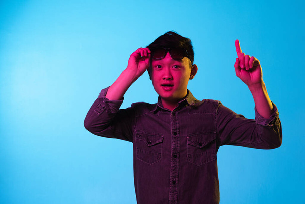 Portrait of Asian young man isolated over blue background in neon light. - Fotó, kép