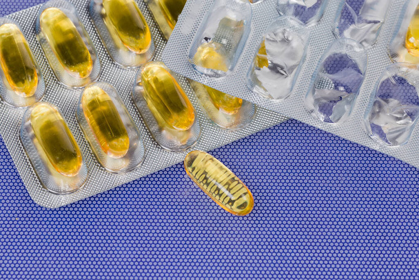 желтые капсулы в блистерной упаковке и одна капсула лежит отдельно - Фото, изображение
