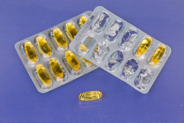 Yellow capsules in blister packing and one capsule lies separately - Photo, Image